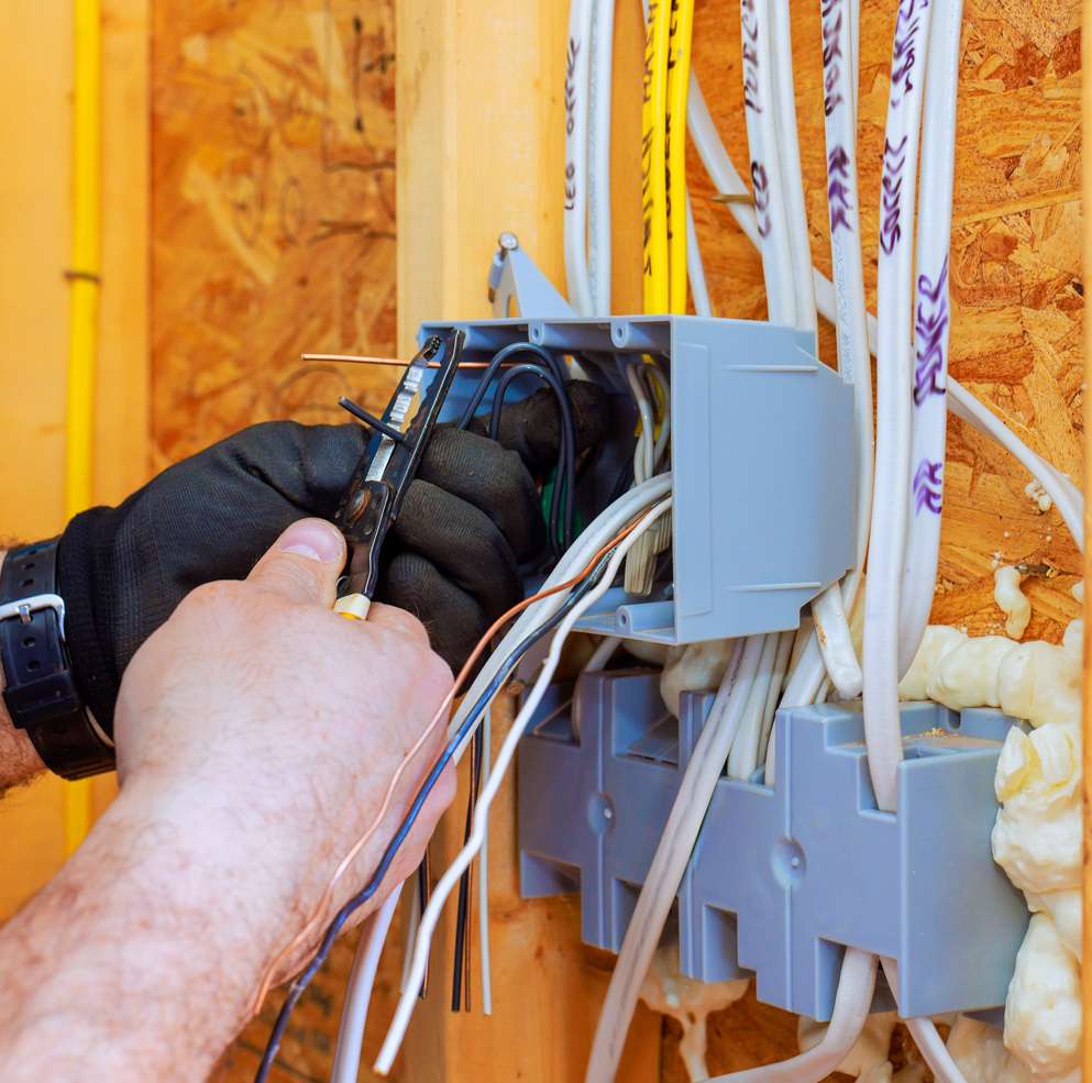 An electrician working on wiring inside a wall